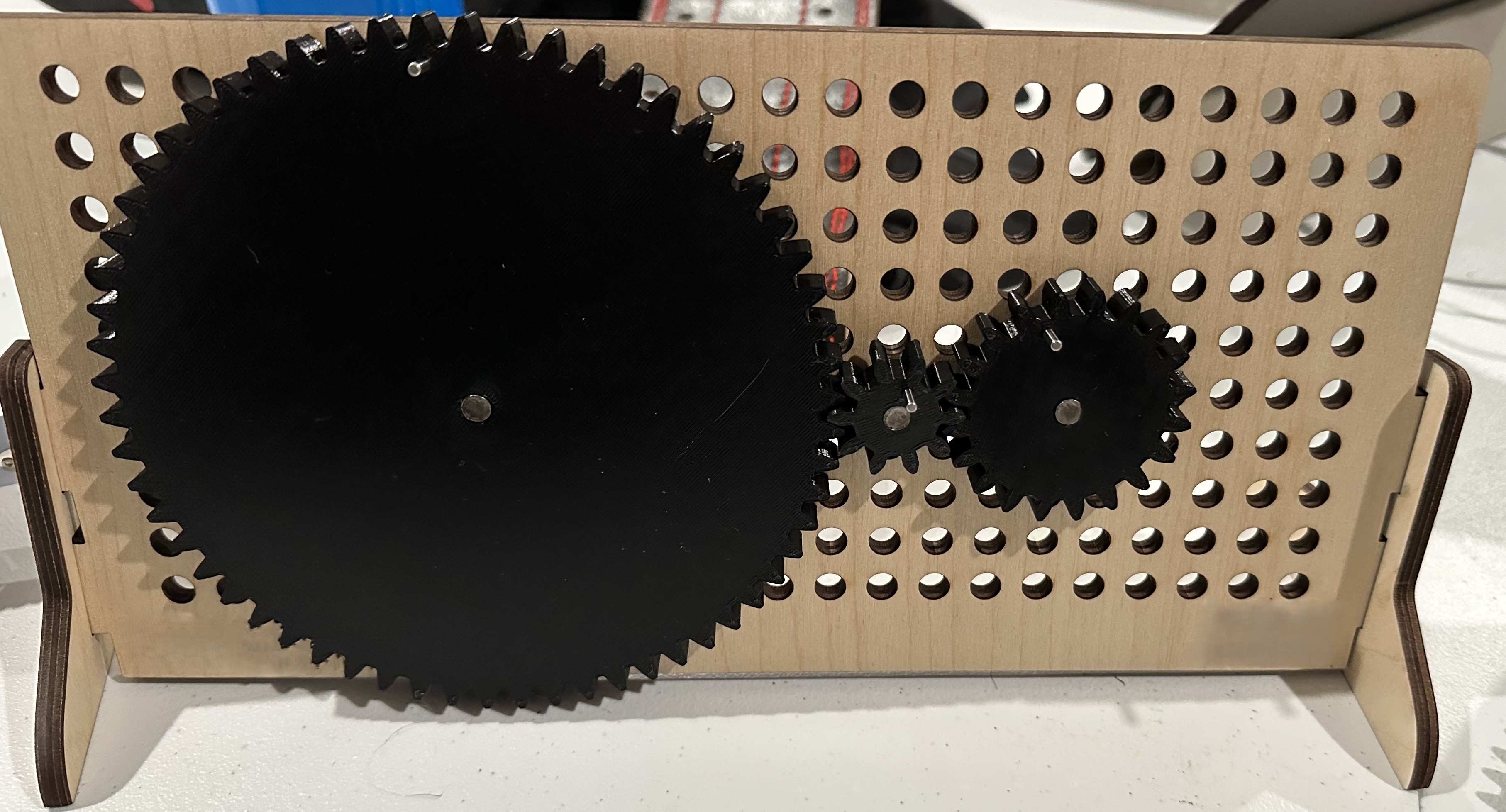 A laser-cut pegboard demonstration tool with 3D-printed gears of varying sizes.